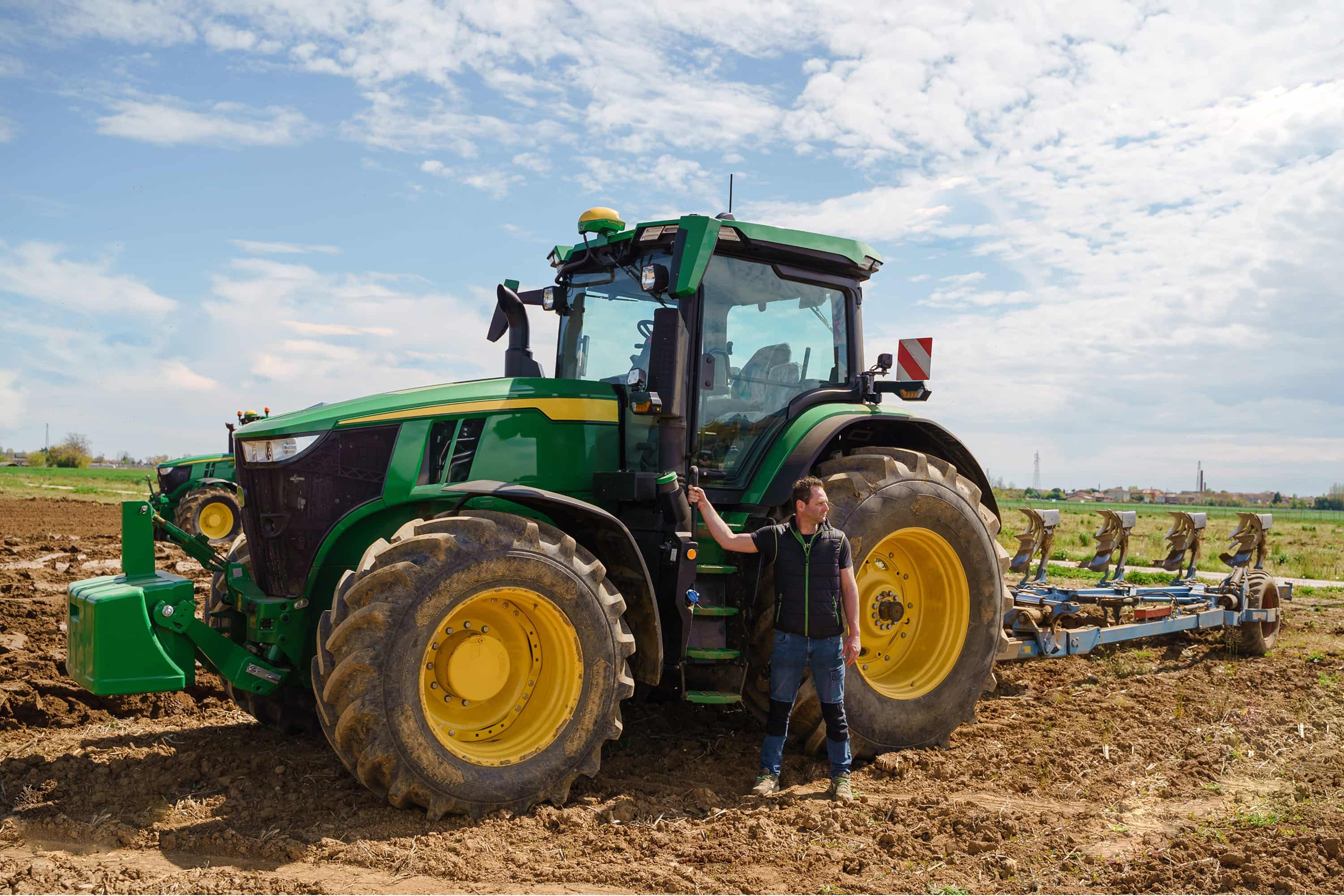 Landwirt neben einem grünen Traktor auf einem Feld